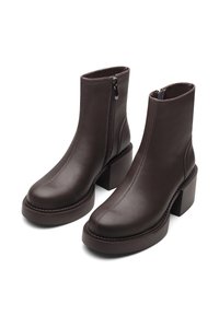 Brown leather ankle boots with a block heel, front zipper, and visible stitching details. Smooth texture with rounded toe and seamless design.