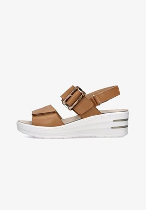 Sandalo con zeppa in pelle color cuoio, con doppie cinghie a fibbia, punta aperta e suola bianca dotata di tre scanalature orizzontali per una maggiore aderenza.