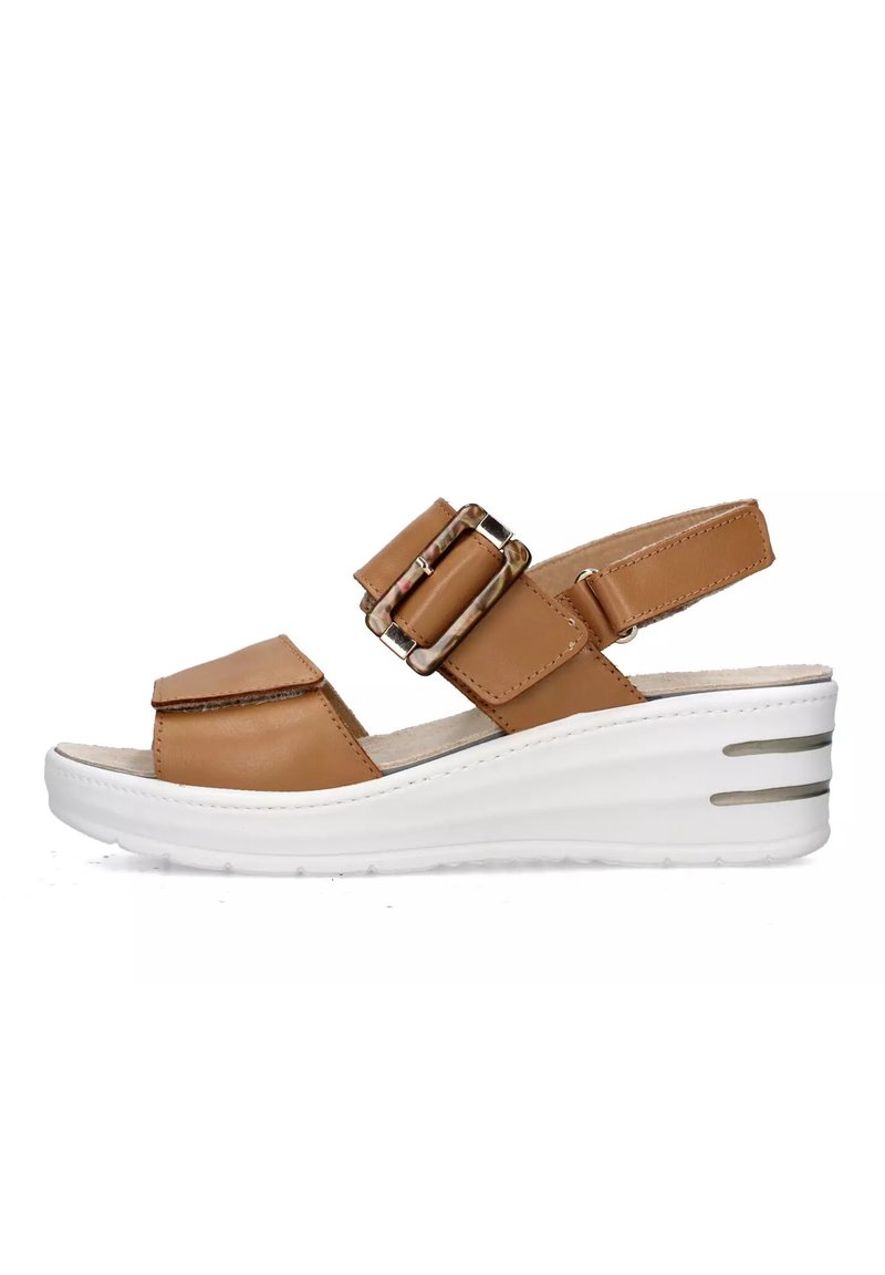 Sandalo con zeppa in pelle color cuoio, con doppie cinghie a fibbia, punta aperta e suola bianca dotata di tre scanalature orizzontali per una maggiore aderenza.
