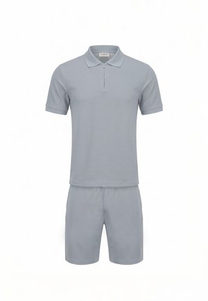 Jasnoszara koszulka polo z krótkim rękawem i zamkiem błyskawicznym oraz pasujące spodenki do kolan, pokazane na białym tle.
