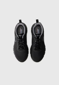 Black athletic shoes with a mesh upper, textured surface, lace-up design, and cushioned sole. Features a slightly elevated back and logo details.