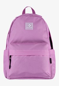 Roza tkaninska nahrbtnik s sprednjim žepom na zadrgo, ki ima značko Converse in zgornjo ročico. Gladka tekstura, klasična oblika.