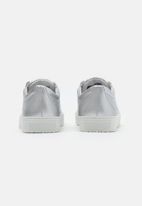 Basket en métal argenté avec une texture lisse et brillante, dotée d'une semelle en caoutchouc blanche et d'accents texturés au niveau du talon pour une meilleure adhérence.