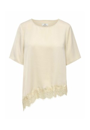 Krémová blúzka s krátkym rukávom, okrúhlym výstrihom a asymetrickým lemom zdobeným vlnitou čipkou na jednej strane.