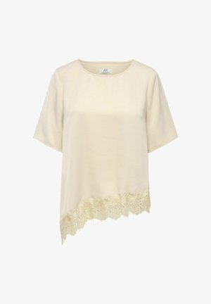Blouse crème à manches courtes avec encolure ronde et ourlet asymétrique orné d'une bordure en dentelle festonnée sur un côté.