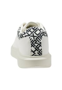 Białe sneakersy o teksturowanym, błyszczącym wykończeniu; charakteryzują się czarno-białym wzornikiem na pięcie, okrągłym kształtem i grubą, białą podeszwą.