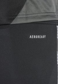 Zwarte sportshorts met een aansluitend design, voorzien van een grijze patroonkleurige panel en het "AEROREADY" logo in het wit gedrukt. Soepele textuur.