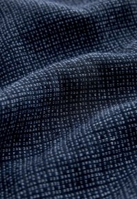 Tissu bleu foncé avec un motif tissé texturé en forme de grille et des plis subtils créant des plis doux.