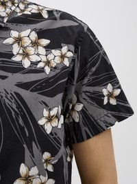 Chemise noire à manches courtes avec un motif floral blanc et jaune, fabriquée en coton doux et dotée d'une coupe décontractée.