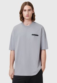 T-shirt surdimensionné gris clair en coton doux. Avec un col rond et un logo imprimé sur la poitrine gauche. Manches courtes.