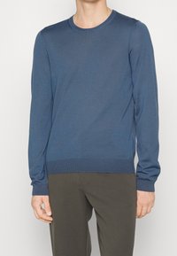 Modrý svetr s dlouhými rukávy vyrobený z hladké, lehké tkaniny. Má kulatý výstřih a žebrované manžety a lem pro přiléhavý vzhled.