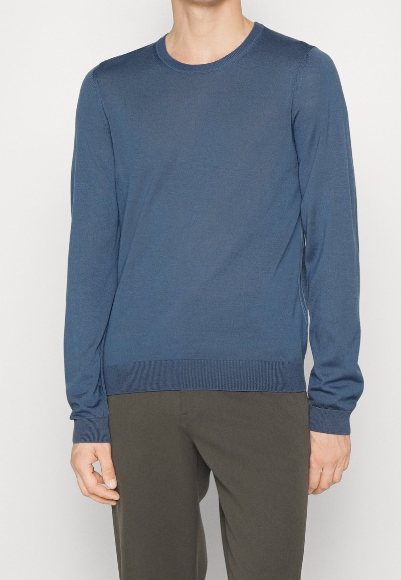 Modrý svetr s dlouhými rukávy vyrobený z hladké, lehké tkaniny. Má kulatý výstřih a žebrované manžety a lem pro přiléhavý vzhled.