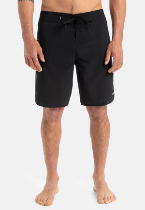 Bermudas negras con un diseño texturizado, cierre con cordón, corte a la altura de la rodilla y un pequeño logo en la parte inferior izquierda.