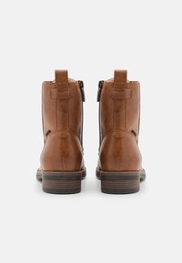 Bottines en cuir brun avec une finition lisse, bouts ronds, talon empilé, fermetures éclair sur les côtés et languettes à l'arrière pour un enfilage facile.