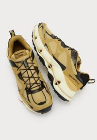 Los zapatos Merrell MATIS presentan un diseño de malla en tonos marrón y negro con una parte superior texturizada, suela curva y un sistema de cordones destacado para un ajuste seguro.