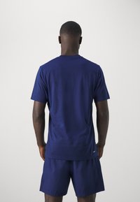 Marinblå t-shirt med kort ärm och normal passform, tillverkad av mjukt material, med rundad halsringning och subtil logotypdetalj vid fållen.