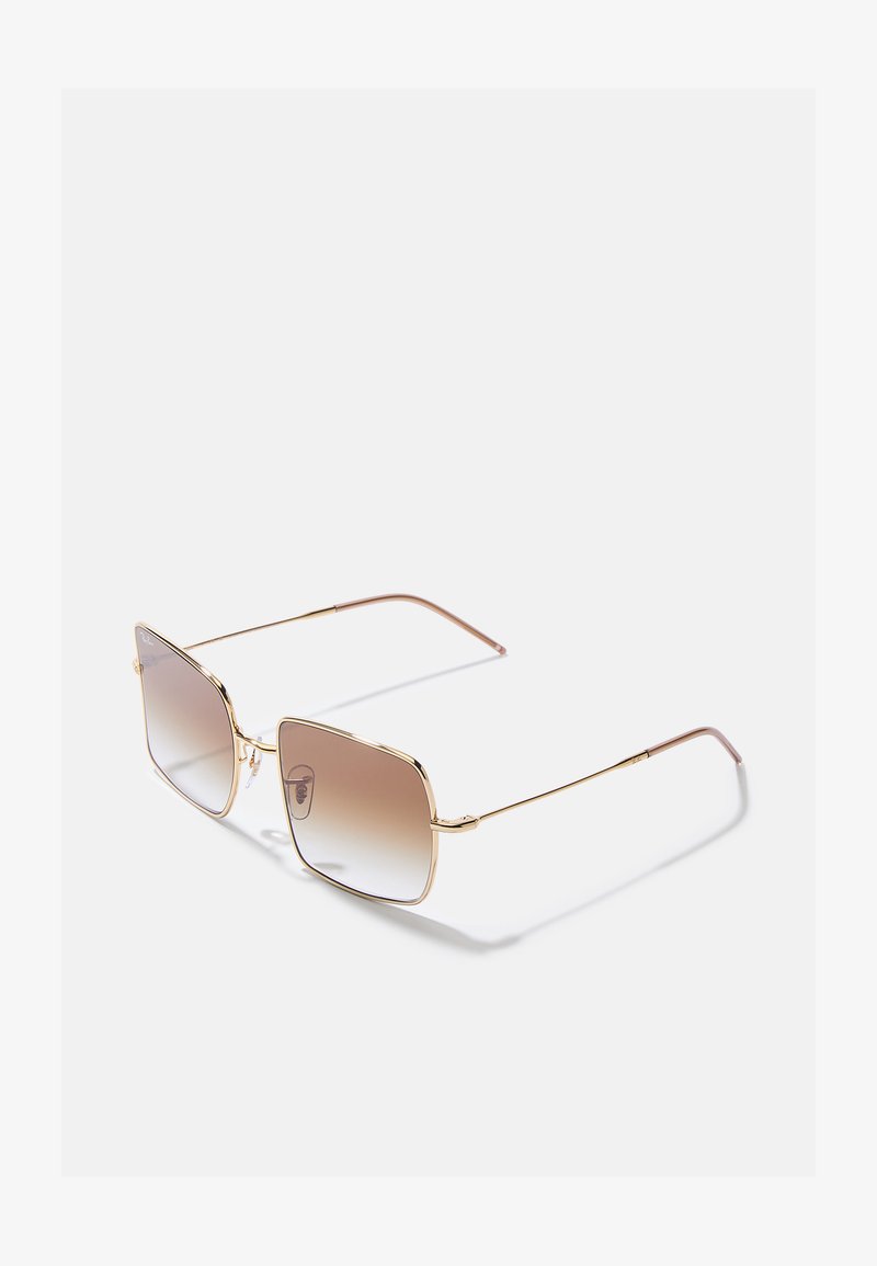 Vierkante zonnebril met gouden metalen details, vergrijsde bruin lenzen en slanke bruine pootjes. Kenmerkt een minimalistisch ontwerp en logo.