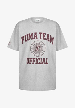 Harmaa puuvillapaita, jossa on "PUMA TEAM" ja "OFFICIAL" viininpunaisella tekstillä, sekä keskellä ympyrälogo. Lyhyet hihat, pyöreä pääntie.