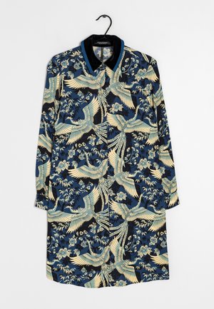 Langärmliges Kleid mit dunkelblauem Hintergrund und cremefarbenem sowie hellblauem Kranich- und Blumenmuster, schwarzer Kragen, hängt an einem schwarzen Kleiderbügel.