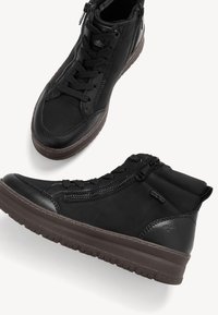 Zapatillas negras de caña alta con un upper de cuero suave, acentos de tela texturizada, cordones delanteros y cremalleras laterales. Suela de goma gruesa y duradera.