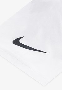 Balts kokvilnas T-krekls ar melnu Nike logotipu uz piedurknes. Gluda tekstūra, klasiskā piegriezuma un izšūta apmale.