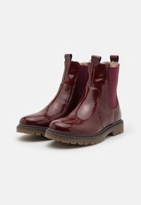 Bottines vernis bordeaux avec des panneaux latéraux en élastique et des languettes, dotées d'une semelle en caoutchouc texturé et d'un intérieur doux.