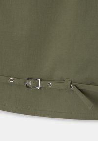 Tessuto verde oliva con una superficie liscia. Presenta una fibbia in metallo e un nastro di tessuto nella parte inferiore, insieme a occhielli in metallo per la regolazione.