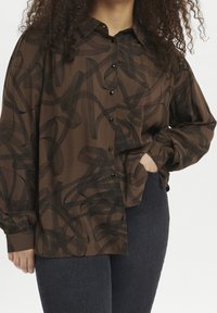 Brown button-up shirt with black abstract swirl pattern, long sleeves, and a pointed collar. Made of lightweight fabric.