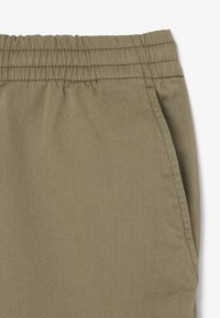 Beige katoenen broek van een katoenmix met een elastische tailleband, voorzien van een zijzak en een gladde, gestructureerde stof.
