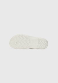 Weiße Sneaker-Sohle mit einem strukturierten, Zickzack-Profil. Glatte Oberfläche mit einem kreisförmigen Detail in der Mitte. Einfaches und minimalistisches Design.
