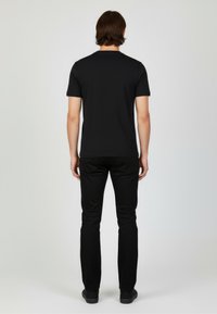 Black short-sleeve t-shirt paired with black slim-fit trousers. Smooth fabric with a simple design. Flat seam detailing, no visible logos.