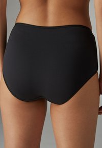 Czarne majtki z wysokim stanem wykonane z gładkiej tkaniny, z falowanym wykończeniem wzdłuż pasa i bezszwową konstrukcją dla komfortu.