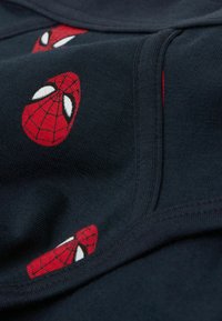 Marineblaues Material mit mehreren roten Spider-Man-Masken und weißen Akzenten, glatte Textur und flache Nähte. Nahaufnahme zeigt die Designdetails.