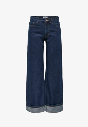 Tumed sinised laiade säärtega teksad volditud äärega, ees taskud, nööpidega kinnis ja vöökohal nähtav marki etikett.