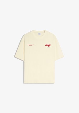 Cream-colored short-sleeve T-shirt with red text "WEARABLE ARTIFACTS SINCE 1998" on left chest and stylized "mg" logo on right chest.