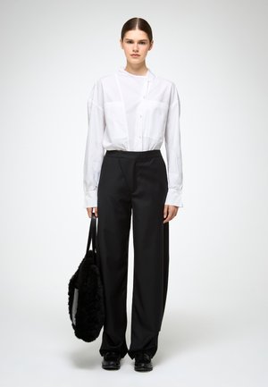 White button-up shirt with a collar, paired with high-waisted black wide-leg trousers. Model holds a black, fuzzy handbag.