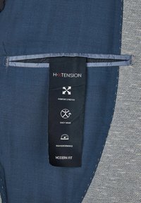 Marine-blauem Stoff mit einem strukturierten grauen Paneel präsentiert das H-XTENSION-Label. Das Label hebt die Merkmale von Komfortstretch und modernem Schnitt hervor.