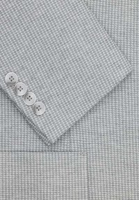 Jasnoszara tkanina w kratkę pchełkę z czterema jasnoszarymi guzikami na rękawie marynarki nad pasującą kieszenią.