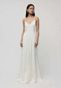 Weißes, bodenlanges Kleid mit V-Ausschnitt, dünnen Trägern und einem weich fließenden Stoff. Mit einem Schlitz vorne und glatter Textur.