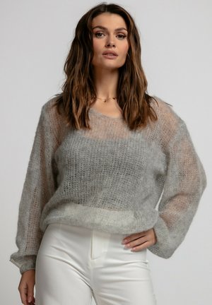 Jasnoszary sweter dziany o luźnym kroju, transparentnej strukturze, szerokich rękawach i miękkim wykończeniu, w połączeniu z białymi spodniami z wysokim stanem.