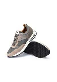 Zapatillas de deporte de ante gris y malla con una mediasuela blanca, suela texturizada gris y acentos en color marrón. Presentan cordones y un logo en la lengüeta.