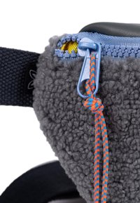 Tejido de forro polar gris con superficie texturada, que presenta un zipper azul y un cordón de tirador con un patrón naranja y azul, adjunto a una correa negra.