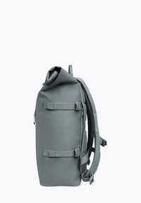 Mochila impermeable gris con diseño de parte superior enrollable, correas ajustables y acolchadas, y bolsillo con cremallera lateral; cuenta con costuras reforzadas y una base resistente.