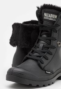 Bottines noires en cuir texturé avec un col en fourrure, dotées d'œillets ronds, de lacets et d'une semelle robuste pour une meilleure adhérence.