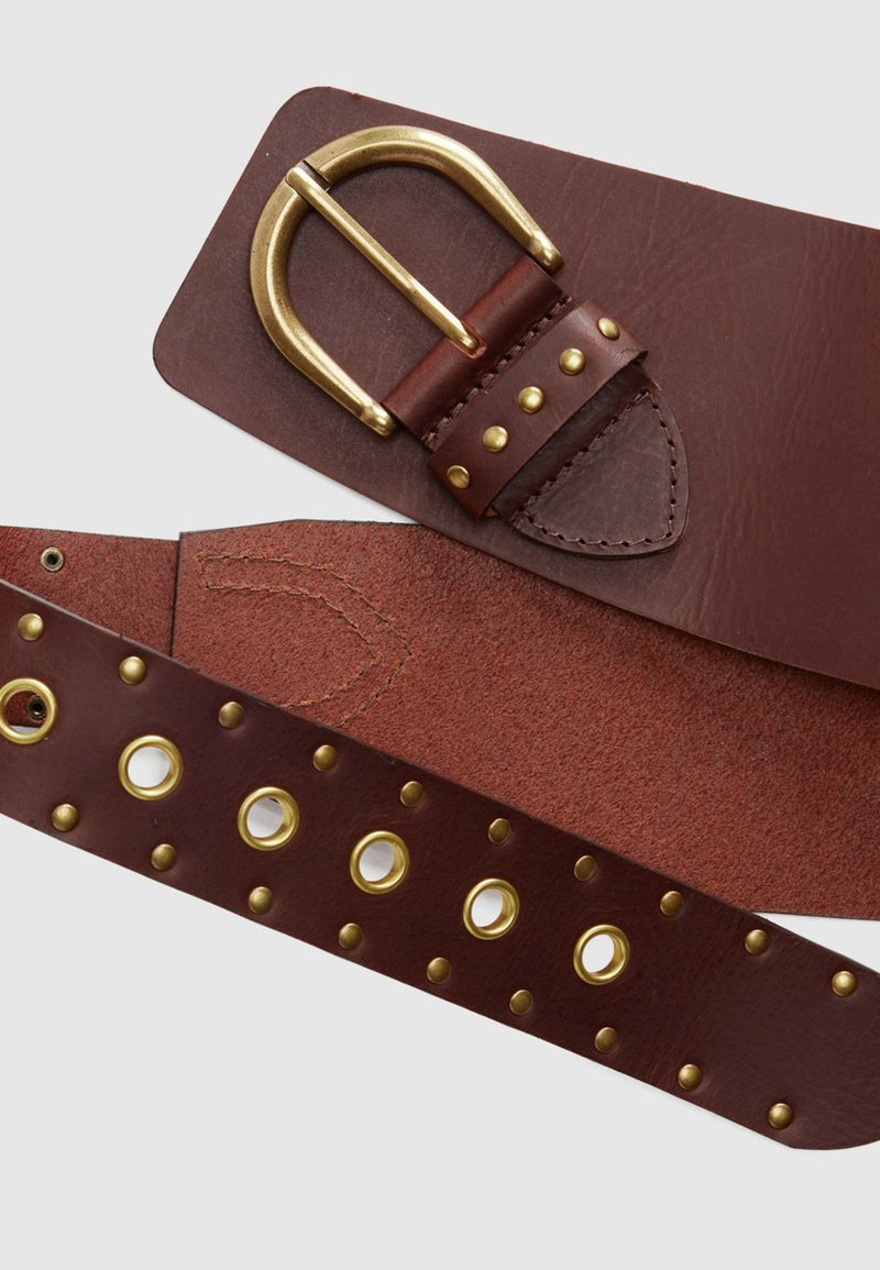 Ceinture en cuir marron avec une boucle en métal doré, ornée de clous et d'œillets le long de la sangle, présentant une surface texturée.
