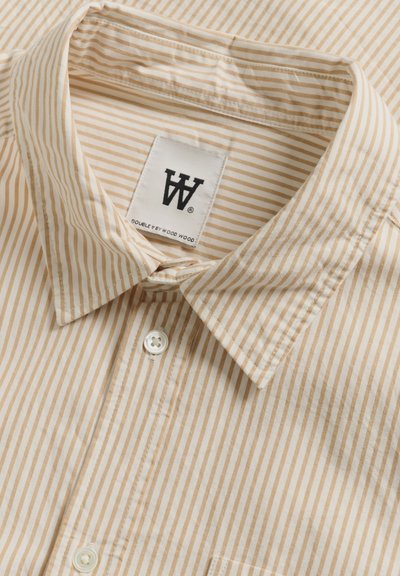 Chemise à rayures beige et marron clair, dotée d'un col pointu, d'une poche avant unique et d'une étiquette en tissu avec logo.