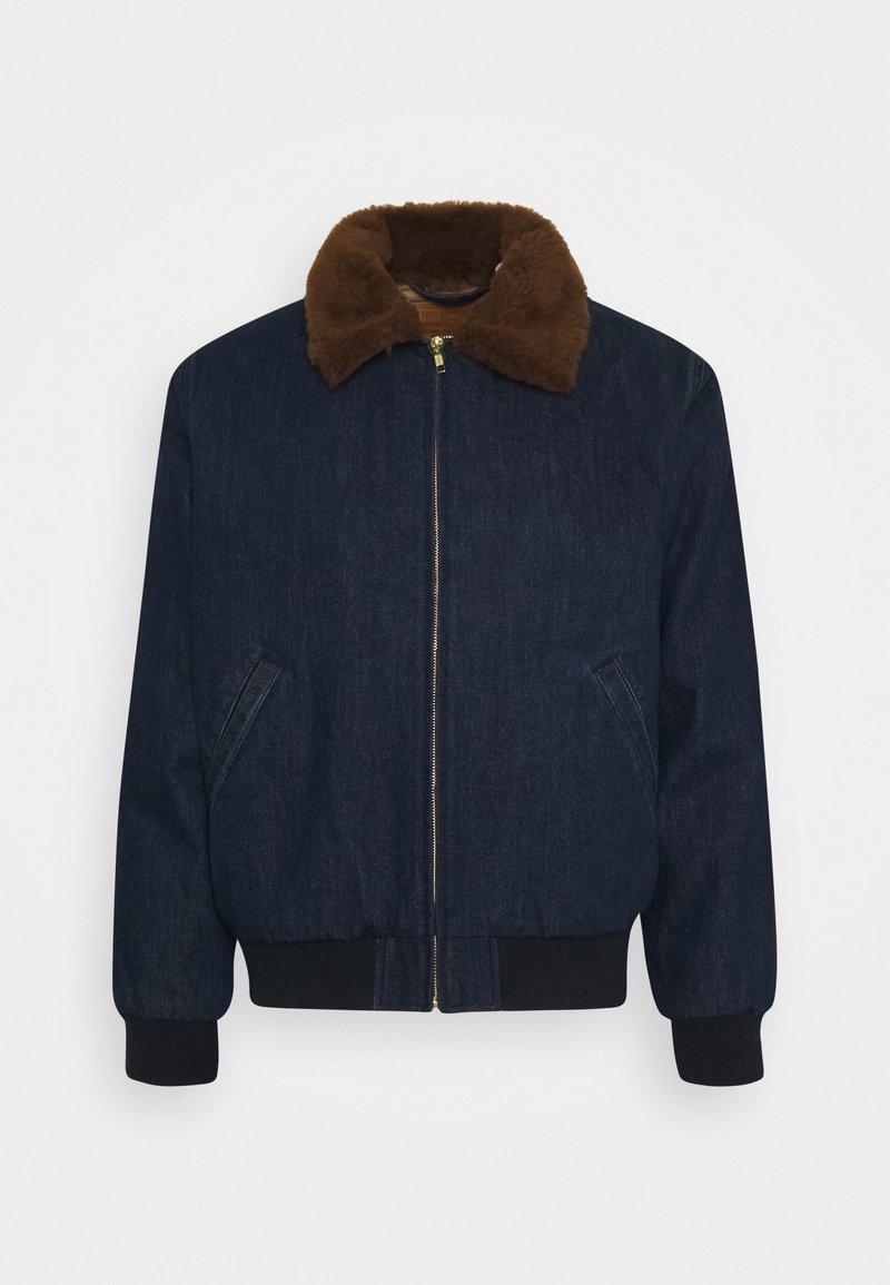 Džínová bomber bunda v tmavě modré barvě s límcem z hnědé umělé kožešiny, předním zipem a žebrovanými manžetami a lemem. Obsahuje boční kapsy.