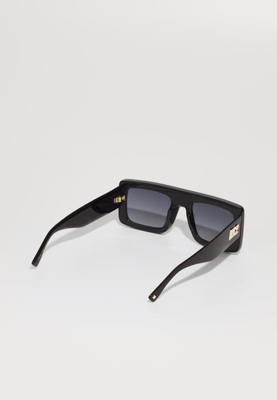 Black sunglasses with a chunky rectangular frame, gradient grey lenses, and gold hardware accents on the temples. Smooth matte finish.