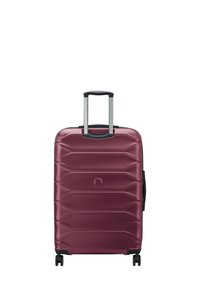 Valigia rigida color bordeaux con una texture a onda, manico estraibile allungabile e quattro ruote girevoli nere.