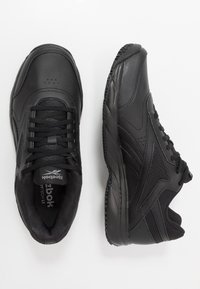 Zapatos deportivos negros con parte superior de cuero sintético, detalles texturizados, diseño con cordones, cuello acolchado y suela de goma para tracción.